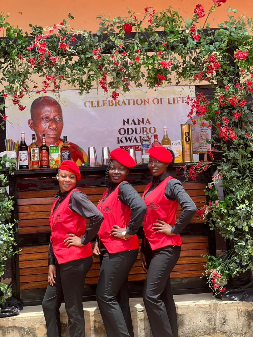 Three King's Protocol officers posed beneath a floral arch